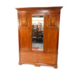 An Edwardian mahogany and inlaid double wardrobe, the outswept pediment over a single mirrored door,