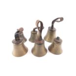 Six hand bells, hammers lacking, four with tooled leather handles, two lacking handle strops.
