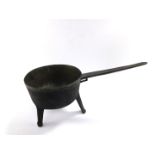 A Georgian bronze saucepan, with engraved decoration to the handle, raised on fluted tripod feet,