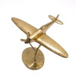 A brass desk stand, modelled as a spitfire, raised on an oval base, 18cm W.