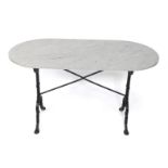 An oval white marble and cast iron table, raised on a shaped supports united by an X frame