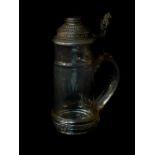 An early 20thC German glass half litre stein, with a hinged pewter lid, with carved scrolling
