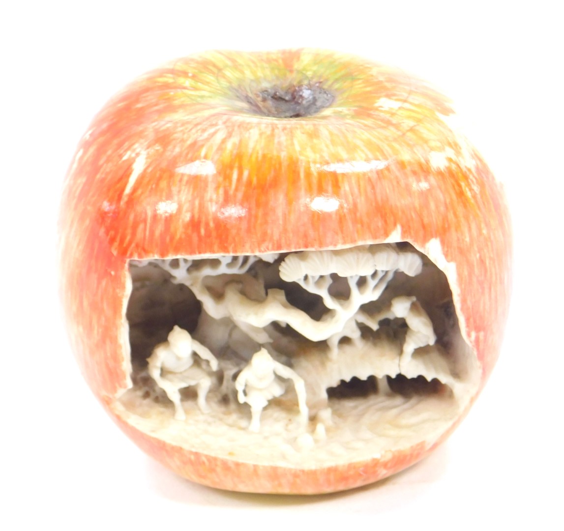 A Chinese 19thC ivory carving of an apple, the front open and showing figures and trees