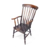 A Victorian oak and elm lath back carver chair, with solid saddle seat, raised on turned legs,