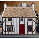 A Tudor style doll's house, with a thatched roof, two storey with four rooms, on a rectangular base,