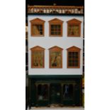 A three storey dolls house, modelled as an antique shop, with furniture and contents, 98cm H, 45cm