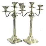 A pair of three branch candelabra, each sconce with gadrooned borders, on a Corinthian column and