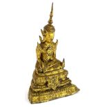 @A gilt metal Indian figure of a seated god, with legs crossed on a stepped base, dressed in finery,