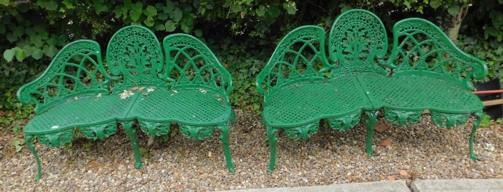 A pair of cast iron garden benches, each with a shaped back and lattice design to the seat, on