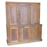 A late 19th/early 20thC stripped pine cupboard, the top with three panel doors, the base with a