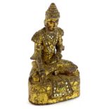 @A gilt metal figure of an Indian figure, with legs crossed, picked out with brass sections, some in