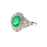 An emerald and diamond platinum dress ring, with central oval cut emerald approx 1.08cts, surrounded