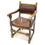 An oak open armchair, with a brown leatherette padded back and seat, on turned legs.