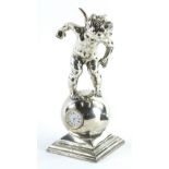 A silver coloured metal mantel clock, cast in the form of a putto on a globe, the movement stamped