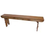 A pine bench, on end supports, 168cm W.