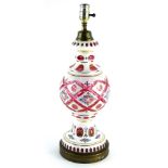 A cranberry tinted and white glass overlay table lamp, decorated with flowers etc., in the