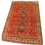 A Persian style rug, with all over design of flowers, roundel's etc., on a red ground with