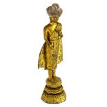 @A gilt metal figure of an Indian god, in standing pose, on a stepped base, picked out with flowers,