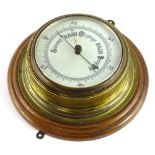 A brass cased aneroid barometer, with circular oak mount, 25cm Dia.