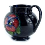 A Moorcroft pottery jug, decorated with red and blue poppies on a navy ground, impressed marks to