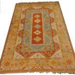 A Turkish carpet, with a design of medallions, flowers etc., in orange, pale blue, cream, one wide
