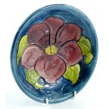 A Moorcroft pottery shallow dish, decorated centrally with a deep red flower, on a navy ground, 19cm