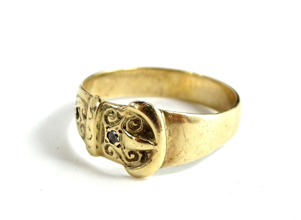 A buckle ring, set with one tiny white stone and one stone missing, yellow metal, unmarked, ring
