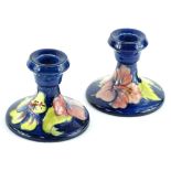 A pair of Moorcroft pottery dwarf candlesticks, each decorated with yellow and pink flowers etc., on