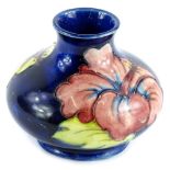 A Moorcroft pottery squat vase, decorated with yellow and red flowers on a navy ground, impressed