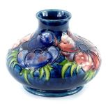A Moorcroft pottery squat vase, decorated with a band of pansies on a blue ground, impressed and
