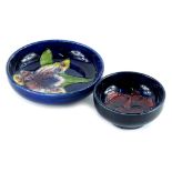 A Moorcroft pottery small dish, decorated centrally with an iris, on a navy blue ground, 12cm dia.