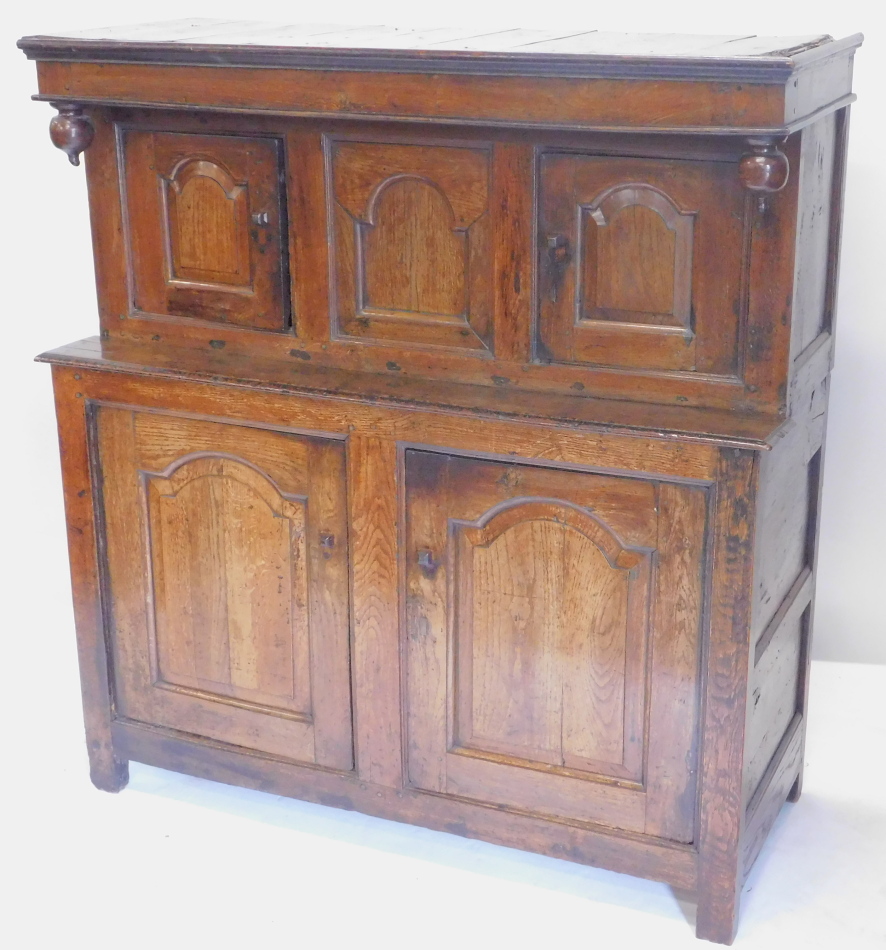 A 17thC oak deudarn, the raised back with three carved panel doors and drop finial's, the base