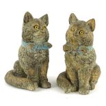 A pair of 19thC cold painted terracotta figures of cats, each wearing a blue bow and with glass