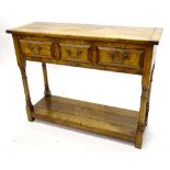 An oak side table, the triple planked top with cleted ends, above three frieze drawers, on turned