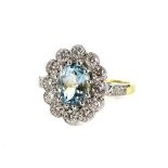 An 18ct gold and platinum aquamarine and diamond daisy ring, with oval cut aquamarine, in claw