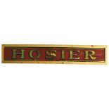 An early to mid 20thC Hosier shop sign, with Verre Eglomise letters, in later frame, 31cm, 174cm W.