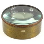 A large glass lens in brass metal casing, 17cm W.