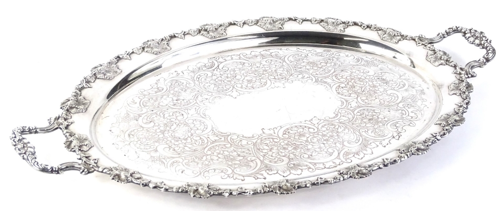 An oval two handled silver plated tray, decorated with a band of vine leaves and grapes, and