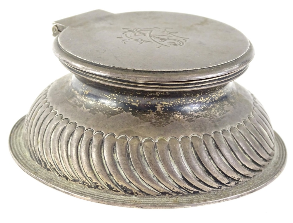 A late Victorian silver inkwell, the hinged lid engraved with a monogram, the base with gadrooned