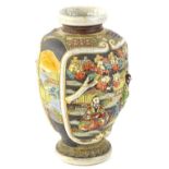 A Japanese earthenware vase, decorated in relief with figures, trees, buildings etc., embellished in