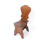 A George II mahogany hall chair, with a shaped back, balloon shaped seat with dished roundel, and