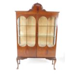 An Edwardian mahogany display cabinet, the shaped pediment over two glazed panelled doors, opening