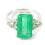 An 18ct white gold emerald and diamond ring, the faceted rectangular cut emerald approx 4.7ct,