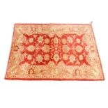 A Pakistan rug, decorated with flowers and leaf tendrils against a red and pink ground, 174cm x