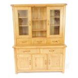 A light oak kitchen dresser, with three shelves, flanked by two glazed doors, enclosing shelves over