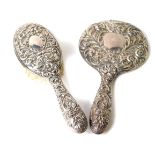 A silver backed hand mirror and clothes brush, embossed with masks, birds, flowers and foliate