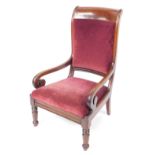 A late Regency mahogany nursing chair, with over stuffed seat and back in red draylon, raised on