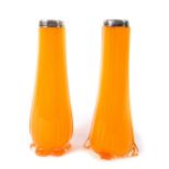 A pair of early 20thC orange glass vases, of vertical fluted teardrop form with silver rims,