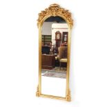 A rococo style gilt wood wall mirror, of domed form, moulded with flowers and scrolling leaves, 71cm