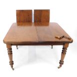 A Victorian mahogany wind out dining table, with two additional leaves, raised on turned legs, brass